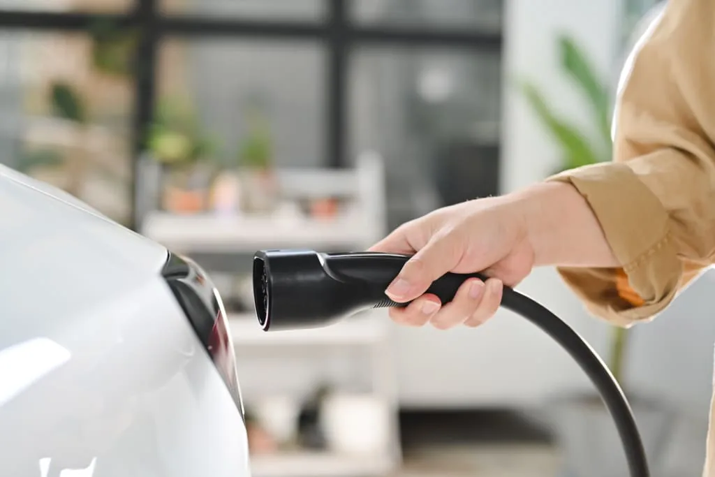 man-plugging-the-charging-cable-into-his-electric